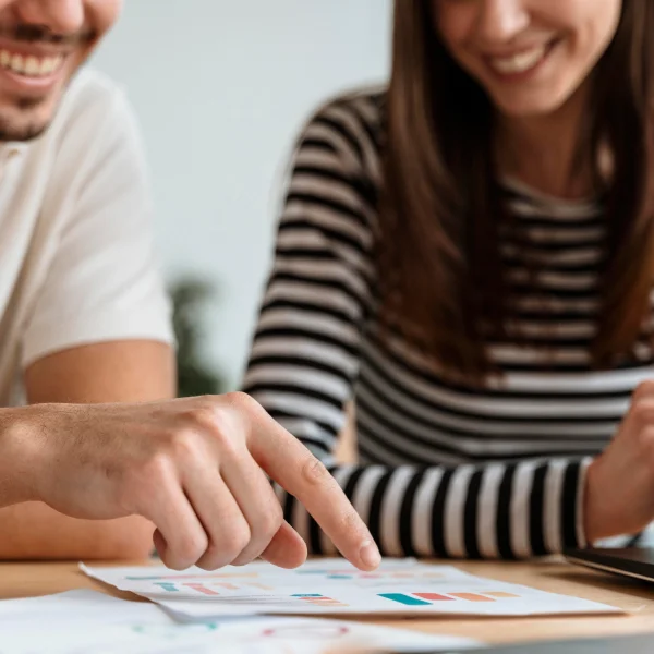Un homme et une femme regardent un écran d'ordinateur portable, discutant de solutions pour sortir de l’endettement.