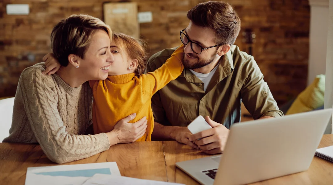 A man and woman sit at a table with a child, discussing ways to manage their tight budget effectively.