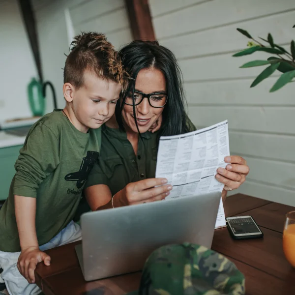 Woman and son reviewing a budget document on a laptop, focused on managing their finances together.