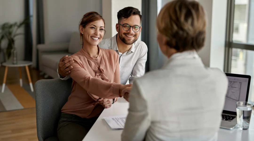 A man and woman shaking hands at a table, symbolizing a business agreement or partnership.