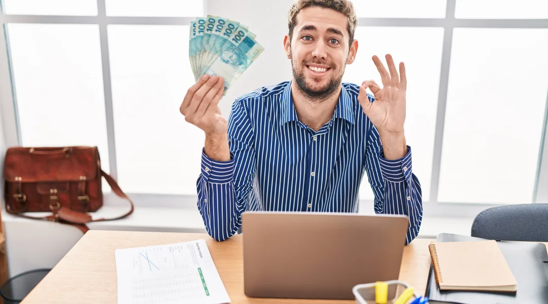 n homme assis à son bureau tient de l'argent dans sa main, prêt pour la consolidation de dettes.