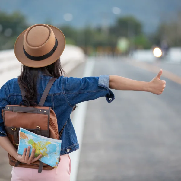 Une femme avec un sac à dos et un chapeau tient une carte, prête à voyager pour vivre des expériences mémorables.