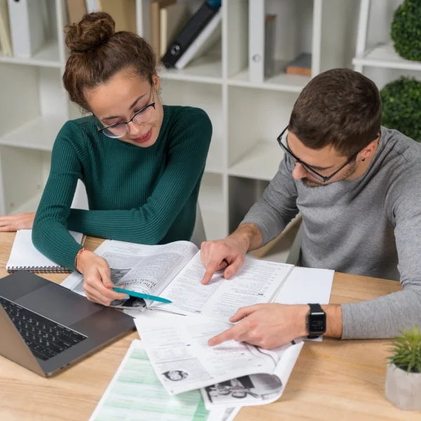 Un homme et une femme travaillent sur des documents à un bureau, discutant d'un prêt personnel au Canada.
