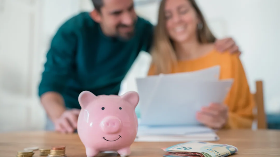 Man and woman examining a piggy bank filled with money, symbolizing savings and personal loans in Canada.